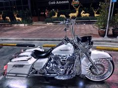 a white and black motorcycle parked in front of a building with deer on the side walk