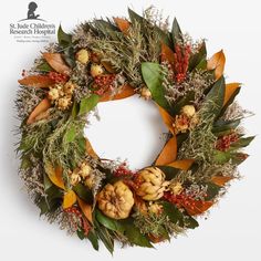 a wreath with leaves, berries and acorns is displayed on a white background