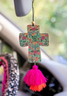 a colorful cross hanging from the front of a car with a tasselled decoration