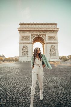 a woman standing in front of the arc de trioe