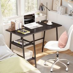 a desk with a laptop computer on top of it next to a chair and window