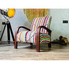 a striped chair sitting on top of a hard wood floor next to a tripod light