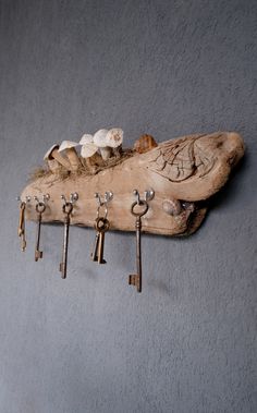 several keys are hanging on a wooden piece with hooks and mushrooms attached to the wall