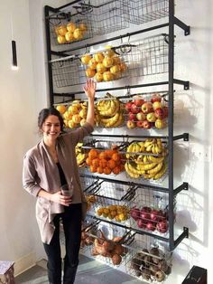 a woman standing in front of a rack full of fruit