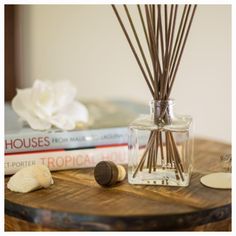 a wooden table topped with two books and a vase filled with reeds