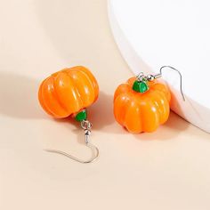 two orange pumpkin shaped earrings hanging from hooks