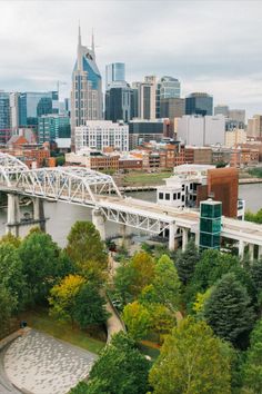 an aerial view of a bridge over a river in a city with tall buildings on the other side