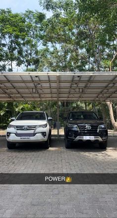 two cars are parked under an awning in the parking lot next to each other