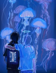 a man standing in front of jellyfish under blue lights with his back turned to the camera