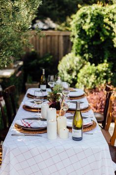 an outdoor table set with wine bottles and candles