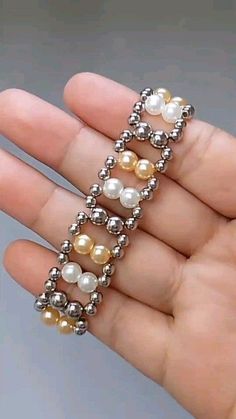 a person is holding some kind of ring in their hand with pearls and beads on it