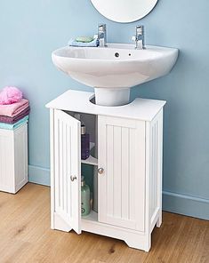 a white sink sitting under a mirror next to a bathroom cabinet with drawers underneath it