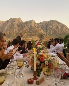 a group of people sitting at a table with wine glasses and food in front of them