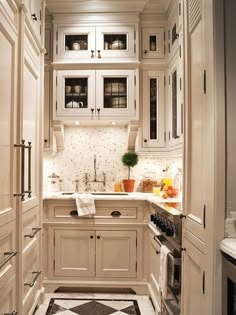 a narrow kitchen with white cabinets and black and white floor tiles on the walls, along with an oven