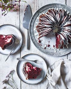 a piece of chocolate cake with white frosting on two plates next to a fork