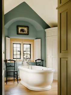 a large white bath tub sitting inside of a bathroom next to a wooden flooring