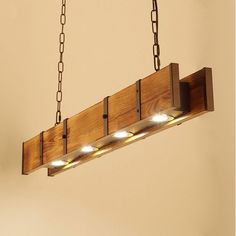 a wooden light fixture with three lights on the bottom and chain hanging from the ceiling