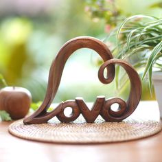 a wooden love sign sitting on top of a table next to a potted plant