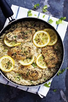 chicken and rice with lemons in a skillet on a blue table cloth next to a fork