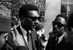 two men in suits and sunglasses talking to each other