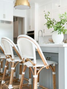 white wicker bar stools are lined up against the kitchen island with gold accents