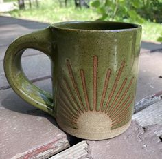 a green coffee mug sitting on top of a wooden table