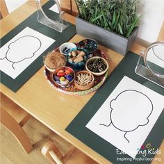 a wooden table topped with paper cut outs and bowls filled with food on top of it