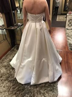 the back of a woman's wedding dress as she stands in front of a mirror