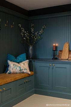 a kitchen with blue painted cabinets and wooden counter tops, along with a bench that has pillows on it