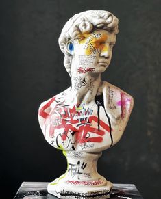 a busturine with graffiti all over it's face and chest is shown in front of a black background