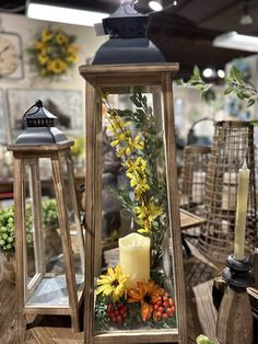 two wooden lanterns with flowers and candles in them sitting on a table next to each other