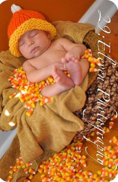 a baby sleeping in a pile of candy corn on top of a wooden floor next to a wall