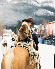 a man riding on the back of a brown horse wearing a fur coat and hat