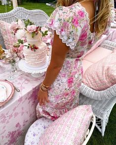 a woman in floral dress leaning over a table with a cake on it