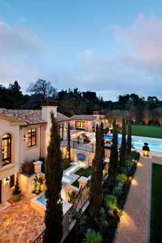 an aerial view of a mansion with pool and landscaping at dusk, taken from above