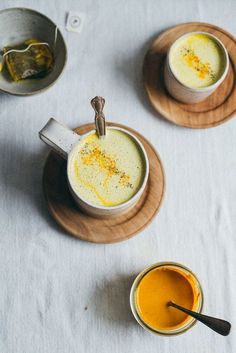 three cups of soup on wooden plates with spoons