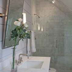 a bathroom with a sink, shower and flowers in the vase on the counter top