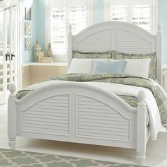 a white bed sitting in a bedroom next to a window with shutters on it