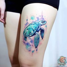 a woman's thigh with watercolor tattoos on it and a green turtle in the middle