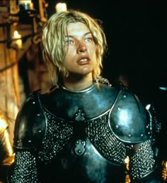 a woman dressed in armor standing next to a man with blonde hair and blue eyes