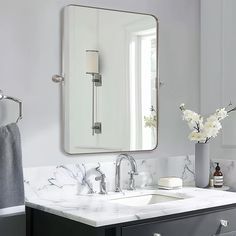 a bathroom with marble counter tops and white walls, along with a large mirror above the sink