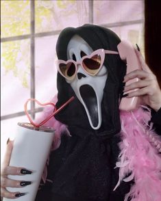 a woman wearing a mask and holding a drink in front of her face with pink feathers