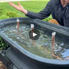 a man sitting in front of a fountain with his hands out to the side,