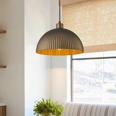 a living room with a couch, table and lamp hanging from the ceiling in front of a window