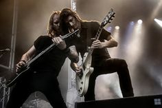 two men playing guitars on stage at a concert