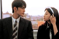 a young man and woman sitting next to each other on a train looking out the window