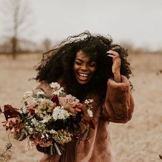 a woman in a field holding a bouquet of flowers on her head and smiling at the camera