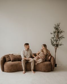 a pregnant couple sitting on a couch in their living room