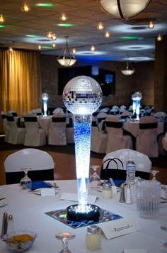 a disco ball on top of a table in a room with white tables and chairs