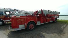 two fire trucks parked next to each other on the side of a road near water